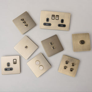 Brass Bee Antique Brass Switches and Sockets in a straight knurled design, featuring various configurations including single and double sockets, power points, and switches, all with a brushed brass finish.