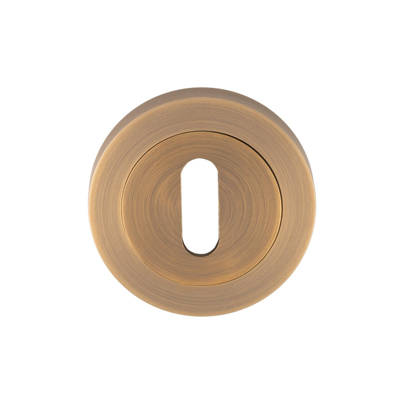 Carlisle Brass Lock Escutcheons in a brushed brass finish, featuring a circular design with a keyhole cutout in the center. Made of durable metal, these escutcheons provide a secure and stylish accent for locking mechanisms.