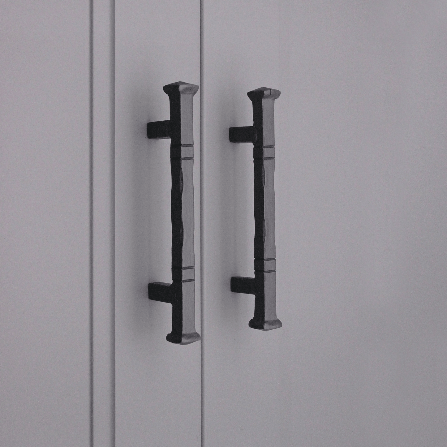 Spira Brass Jade Pull Handle in black, showing a textured design with flat ends for easy grip, mounted on cabinet doors.