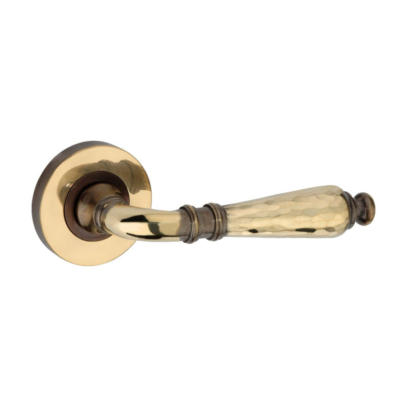 Spira Brass Hammered Hazel Lever on Rose featuring a hammered metal design with a polished brass finish and a round rosette, providing a traditional look for door hardware.