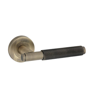 Spira Brass Connaught Lever on Rose with a brushed brass finish and a textured black handle. The lever features a round rose plate for mounting, providing a modern design suitable for doors.