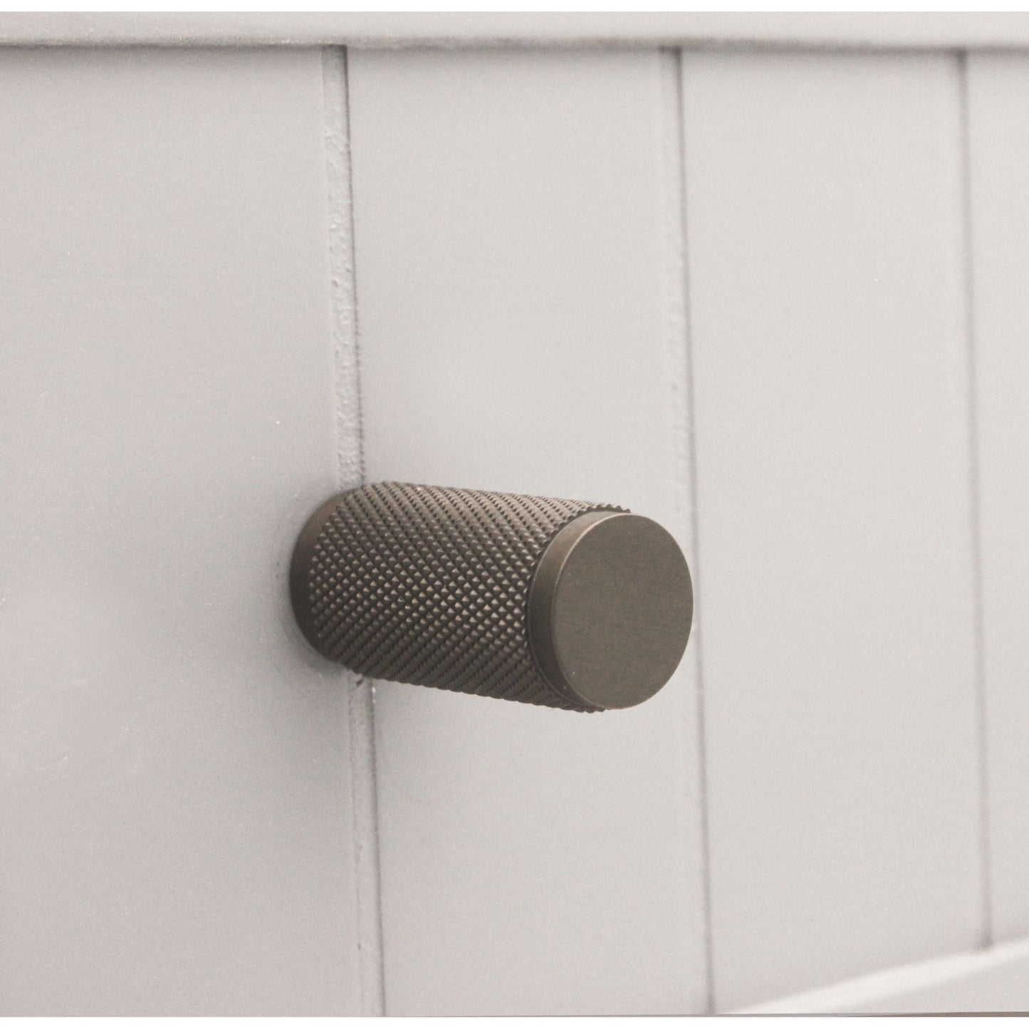 Spira Brass Knurled Cylinder Cupboard Pull in a dark, brushed finish with a textured surface, designed for easy grip.