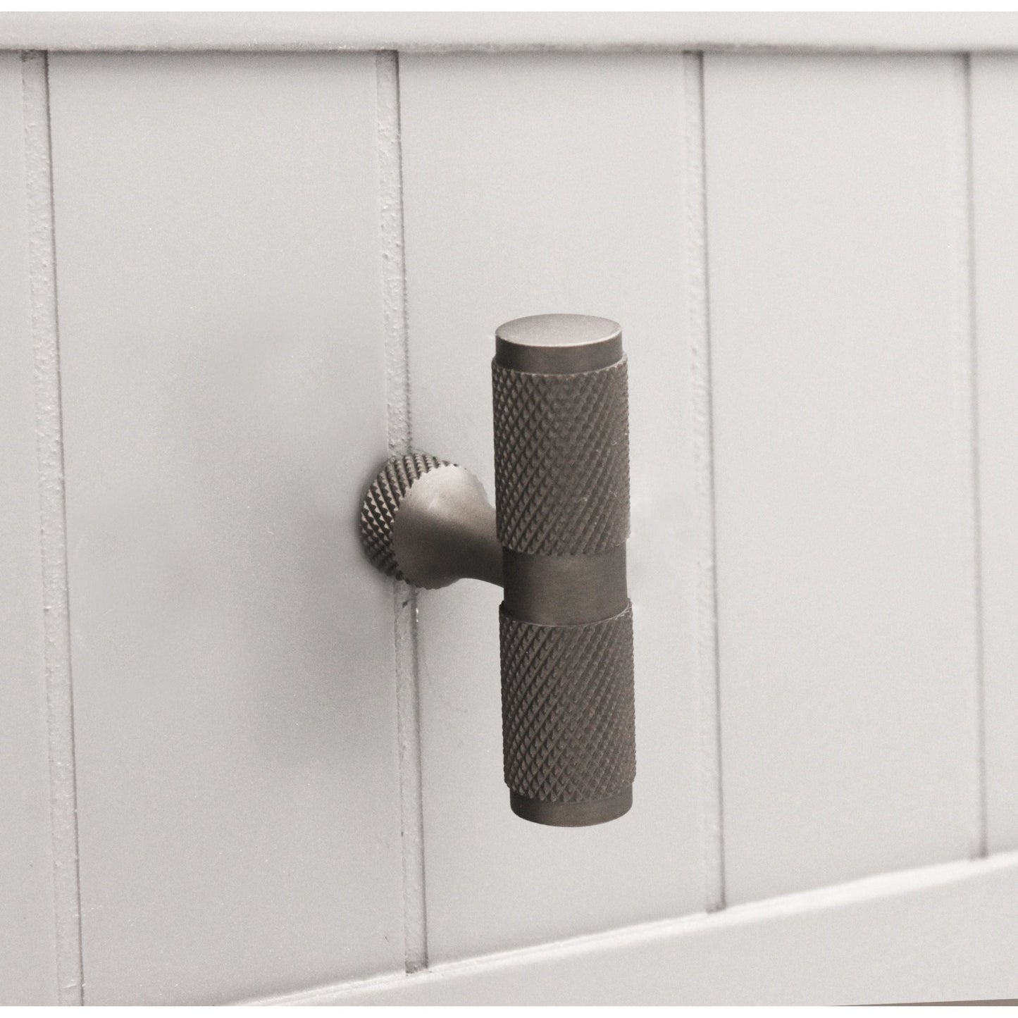Spira Brass Knurled T Bar Cupboard Pull in a muted metallic finish, featuring a textured grip and a round base, designed for added functionality on cabinet doors.