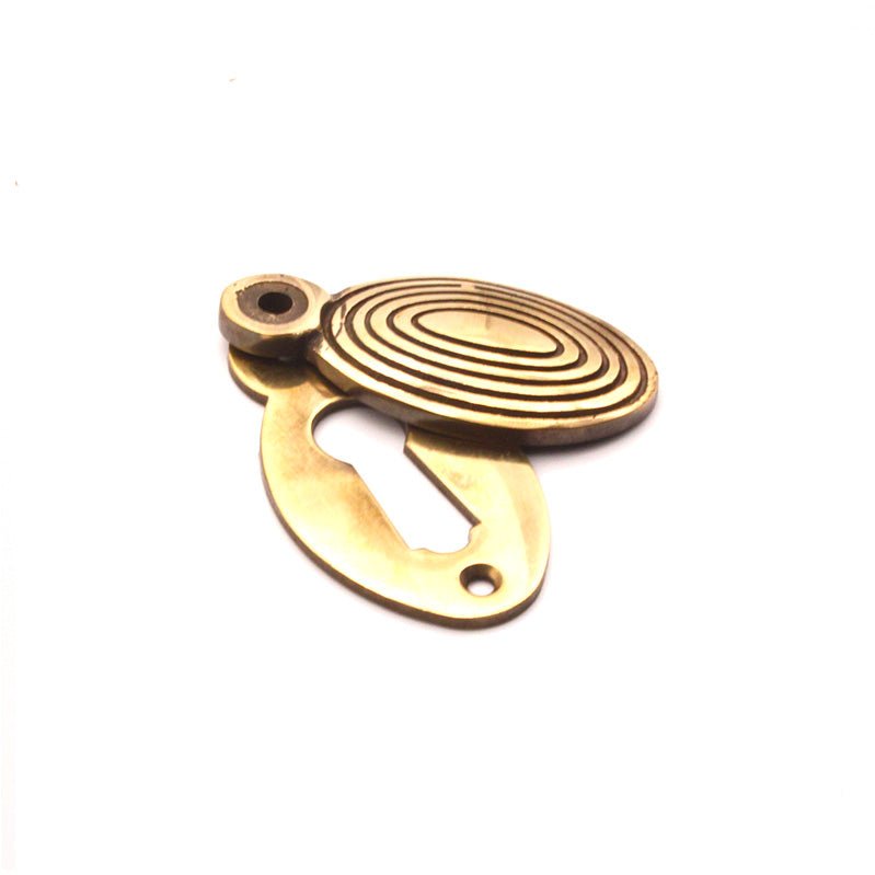 Spira Brass Oval Beehive Escutcheon in polished brass, featuring an oval shape with concentric grooves and a keyhole cutout, typically used for door hardware.