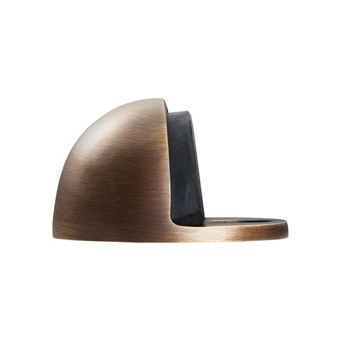 Carlisle Brass Oval Floor Mounted Door Stop in an antique bronze finish, featuring a rounded design with a rubber stop for securing doors.