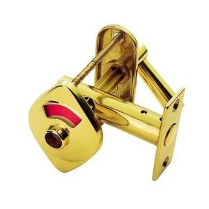 Carlisle Brass Indicator Bolt With Emergency Release in polished gold finish, featuring a circular design with a red indicator and a mechanism for emergency release, installed with a rectangular backing plate.