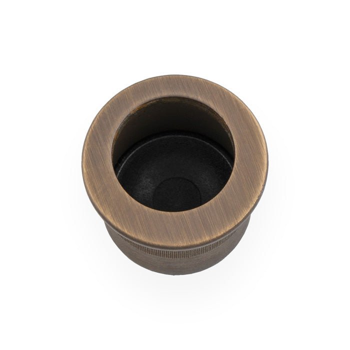 Alexander & Wilks Round Sliding Door Finger Edge Pull in an antique brass finish, featuring a circular design with a black interior, made of durable metal.
