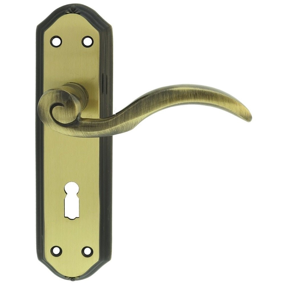 Carlisle Brass Wentworth Lever on Backplate, featuring an antique brass finish with a swirling handle design and a keyhole cutout. The backplate is rectangular with rounded edges, suitable for various door applications.