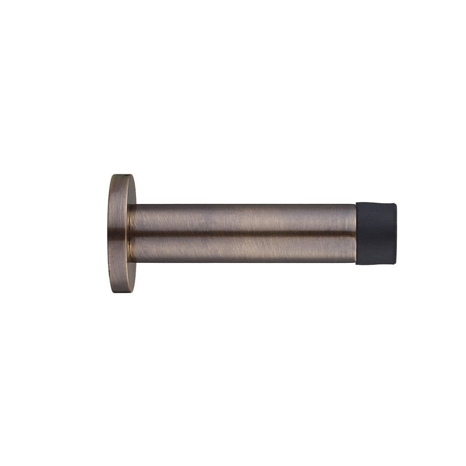 Zoo Hardware Door Stop - Cylinder c/w Rose 80mm in a natural brass finish, featuring a cylindrical body and a rubber tip for grip, designed to secure doors in an open position.