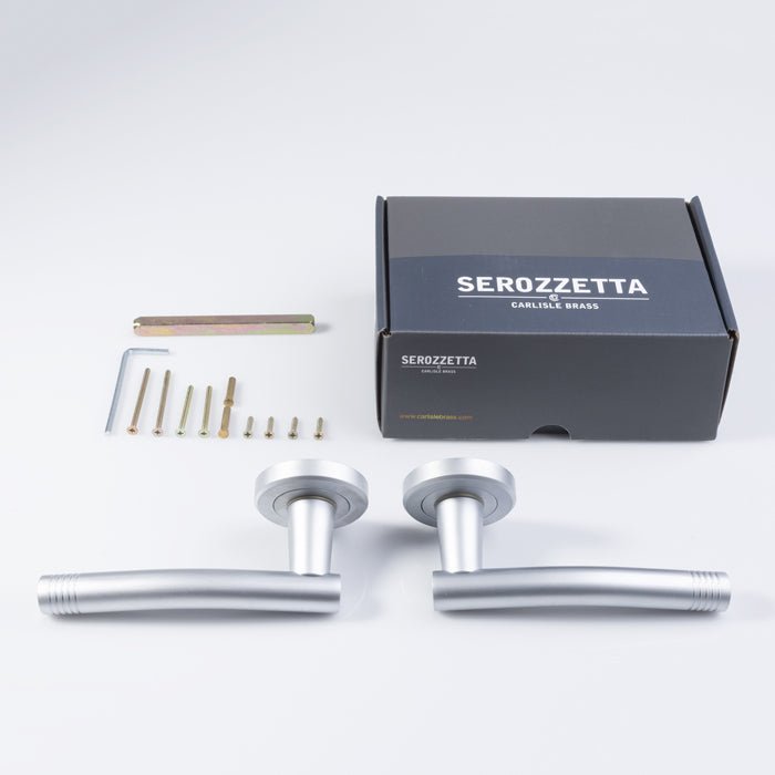 Carlisle Brass Carolina Lever On Rose in a brushed silver finish, featuring two lever handles and a round rose, accompanied by installation fittings, shown with a black Serozzetta box.