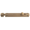 Carlisle Brass Surface Bolt in an antique brass finish, featuring a sliding mechanism with a round knob and multiple mounting holes for secure installation.