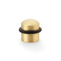 Alexander & Wilks Dome Top Floor Mounted Door Stop in a polished brass finish, featuring a rounded top and a black rubber base for stability.
