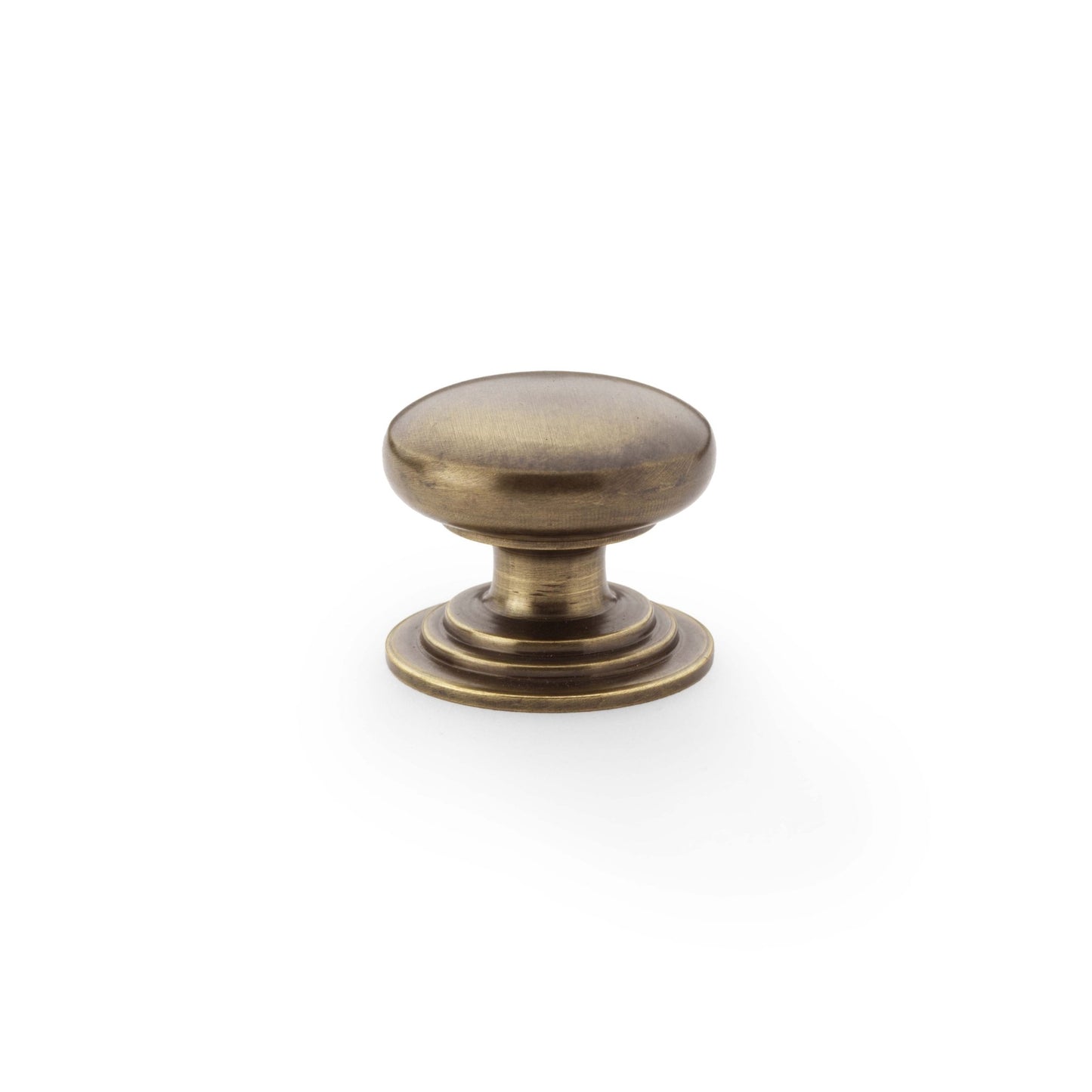 Alexander & Wilks Waltz Round Cupboard Knob on Stepped Rose in a brushed antique brass finish, featuring a smooth rounded top and a stepped base for grip.