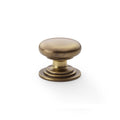 Alexander & Wilks Waltz Round Cupboard Knob on Stepped Rose in a warm antique brass finish, featuring a rounded knob design and a stepped base for easy gripping.
