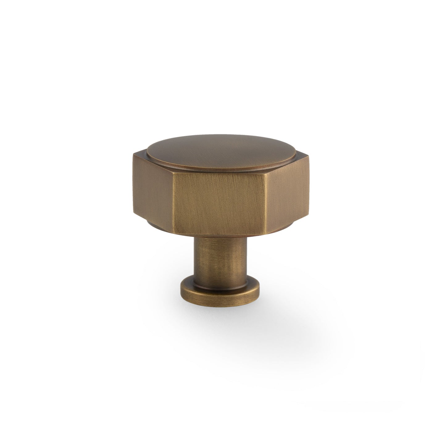 Alexander & Wilks Vesper Hex Cabinet Knob in a warm antique brass finish, featuring a hexagonal top and a cylindrical base, designed for cabinet or drawer applications.