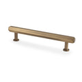 Alexander & Wilks Vesper Hex T-Bar Cabinet Pull in a brushed brass finish, featuring a sleek rectangular design with two cylindrical mounting bases for easy installation.