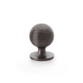 Alexander & Wilks Caesar Cupboard Knob on Round Rose in an oil-rubbed bronze finish, featuring a round shape with horizontal grooves for grip, mounted on a circular base.