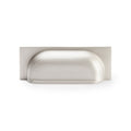 Alexander & Wilks Quantock Cup Handle in a brushed nickel finish, featuring a simple, curved design with a rectangular backplate. The handle is designed for cabinetry and drawers.