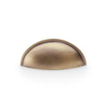 Alexander & Wilks Quieslade Cup Handle in antique brass finish, featuring a curved design that mimics a classic cup shape. The handle is suitable for cabinetry or drawers.