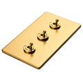 Eurolite Stainless Steel 3 Gang Toggle Switch in satin brass finish, featuring three toggle switches mounted on a rectangular plate with a brushed texture.