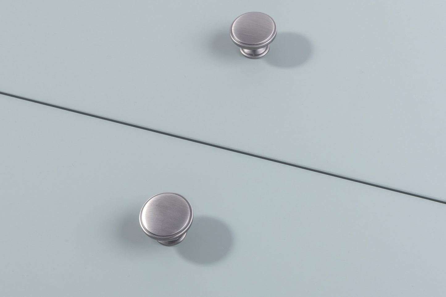 Carlisle Brass Oxford Knob in brushed nickel, featuring a round design with a smooth surface and subtle shimmer, mounted on a light blue surface.