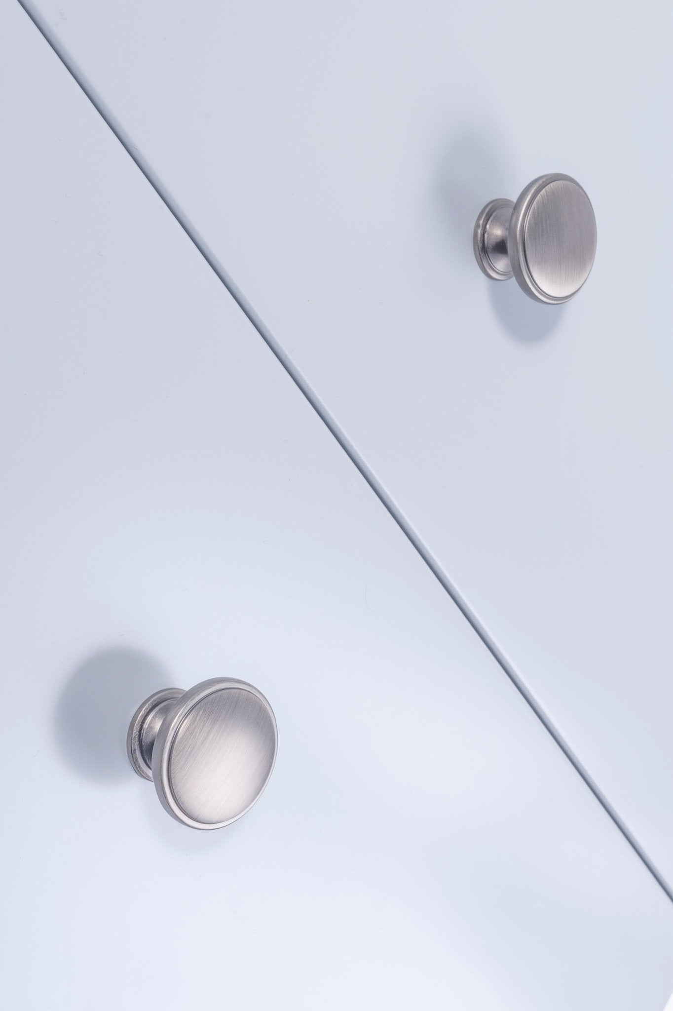 Carlisle Brass Oxford Knob in satin chrome finish, featuring a round shape and smooth surface, installed on a light blue cabinet.