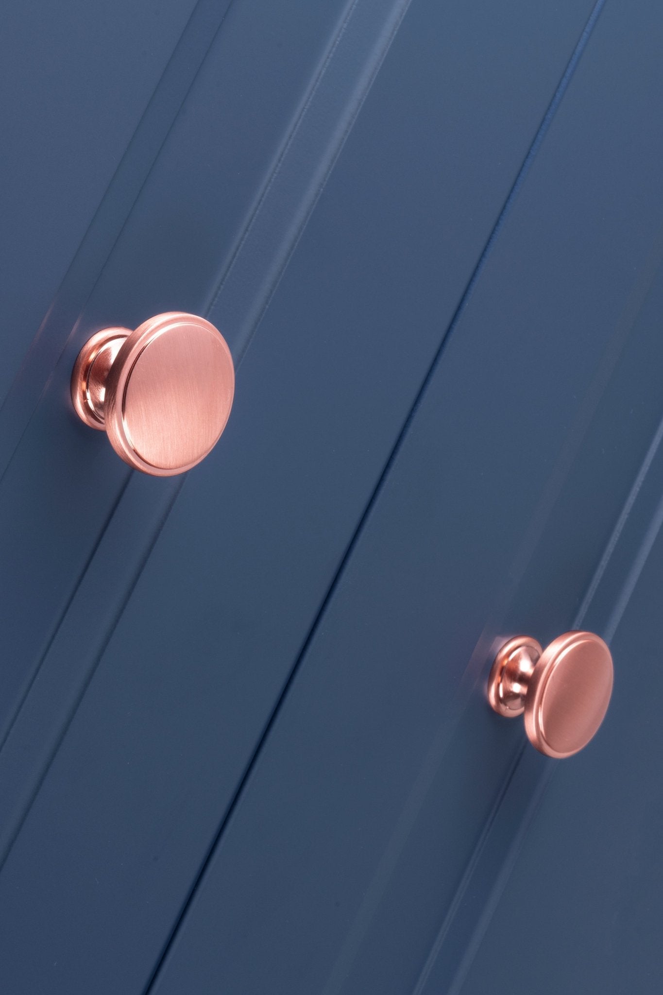 Carlisle Brass Oxford Knob in rose gold finish, featuring a smooth round shape suitable for cabinetry or furniture. The knob is clearly displayed against a blue panel background.