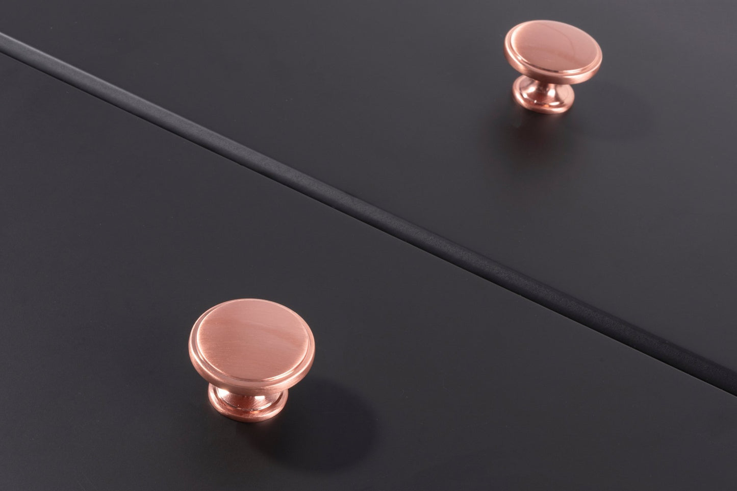 Carlisle Brass Oxford Knob in polished rose gold finish, featuring a smooth round design, mounted on a dark surface.