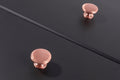 Carlisle Brass Oxford Knob in polished rose gold finish, featuring a smooth round design, mounted on a dark surface.
