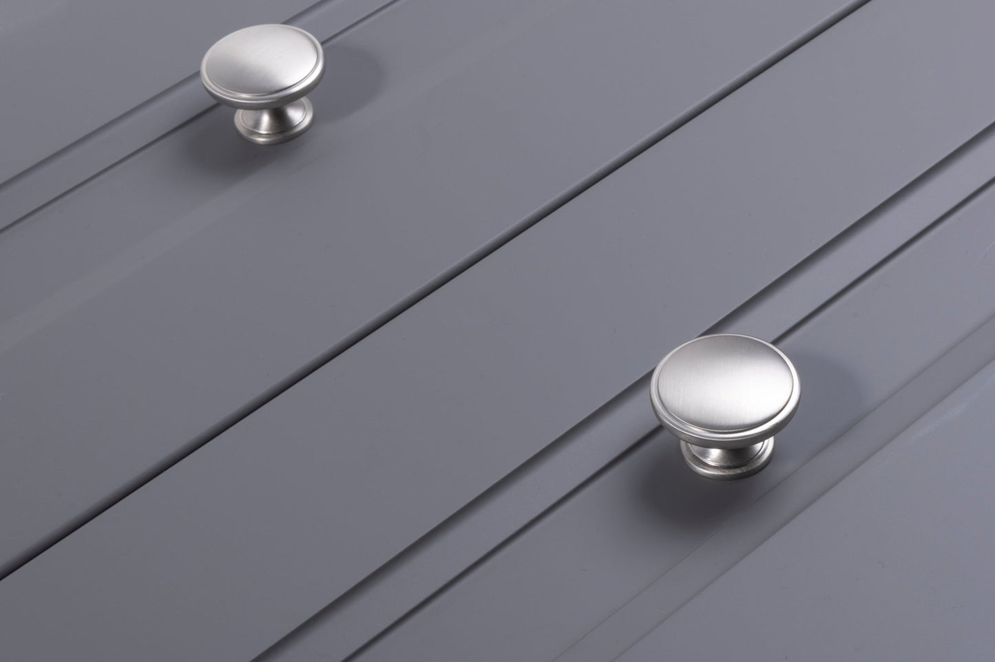 Carlisle Brass Oxford Knob in brushed nickel finish, featuring a smooth rounded design suitable for cabinetry, shown on a gray panel surface.