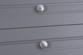 Carlisle Brass Oxford Knob in a brushed nickel finish, featuring a round, flat design installed on gray drawer fronts. The knob is positioned on horizontal lines of the drawers.