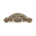 Spira Brass Floral Cup Pull in antique brass finish, featuring a decorative floral design with intricate detailing and two installation holes.
