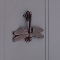Spira Brass Dragonfly Door Knocker in an antique bronze finish featuring detailed dragonfly wings and a textured handle, designed for mounting on doors.