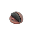 Spira Brass Half Moon Door Stopper in a bronze finish, featuring a round base with a black rubber insert for grip, designed to hold doors open securely.