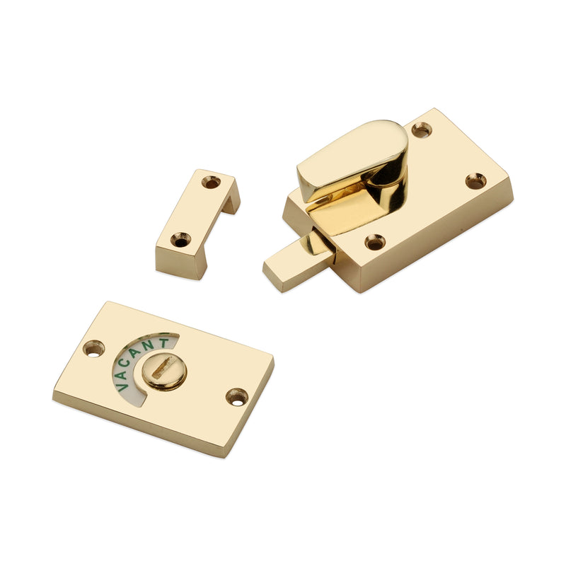 Spira Brass Indicator Bolt Latch in polished brass finish, featuring a release lever and a round indicator plate with 'VACANT' marking, shown with mounting plate and strike plate.