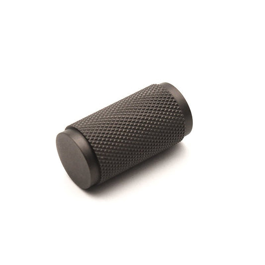 Spira Brass Knurled Cylinder Cupboard Pull in a dark finish, featuring a textured knurled design for grip and a cylindrical shape.
