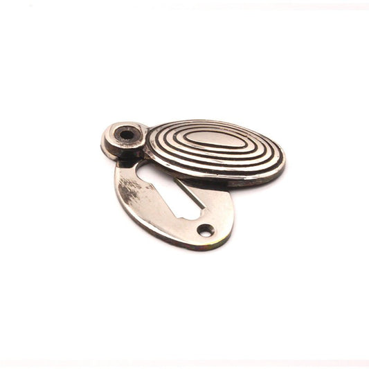 Spira Brass Oval Beehive Escutcheon in a polished finish, featuring an oval shape with concentric lines and a mounting slot for installation.