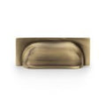Alexander & Wilks Quantock Cup Handle in an antique brass finish, featuring a rounded design and a flat rectangular backplate.