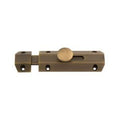 Carlisle Brass Surface Bolt in antique brass finish, featuring a simple design with a round knob for sliding latch mechanism and multiple mounting holes for easy installation.