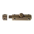 Carlisle Brass Surface Bolt finished in antique brass, featuring a cylindrical handle and a sliding bolt mechanism, designed for secure door fastening.