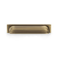 Alexander & Wilks Quantock Cup Handle in antique brass finish, featuring a smooth, curved design that integrates seamlessly with cabinetry. The handle is designed for easy gripping and adds a classic touch to furniture.