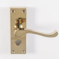 Carlisle Brass Contract Victorian Scroll Lever on Backplate in a polished gold finish, featuring a sleek lever design and a rectangular backplate with visible screw holes and a keyhole.