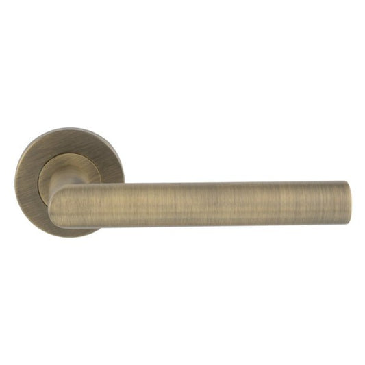 Carlisle Brass Treviri Mitred Round Bar Lever on Sprung Rose in a brushed antique brass finish, featuring a sleek, curved lever design attached to a round rose.