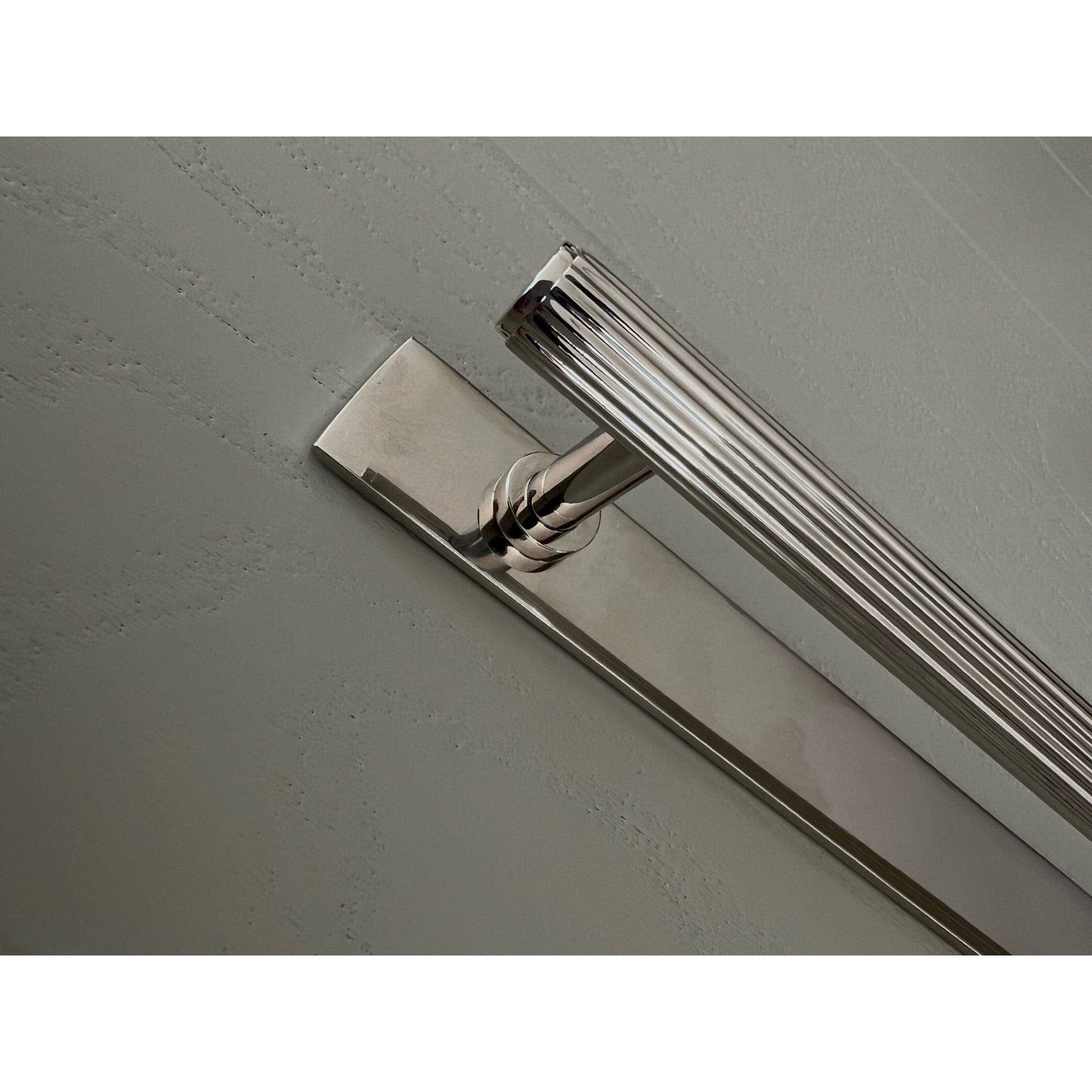 Brass bee Brass Backplate in nickel with 128mm/160mm hole-to-hole handles, featuring a linear design and a polished finish, shown attached to a textured wall surface.