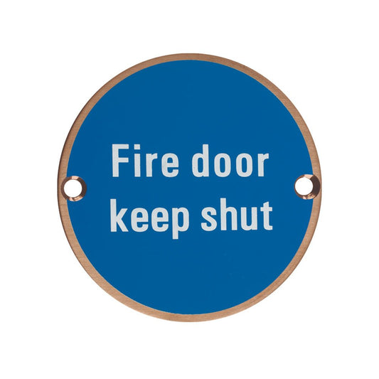 Zoo Hardware Fire Door Keep Shut Sign in round shape with a blue background and white text, featuring two holes for mounting.